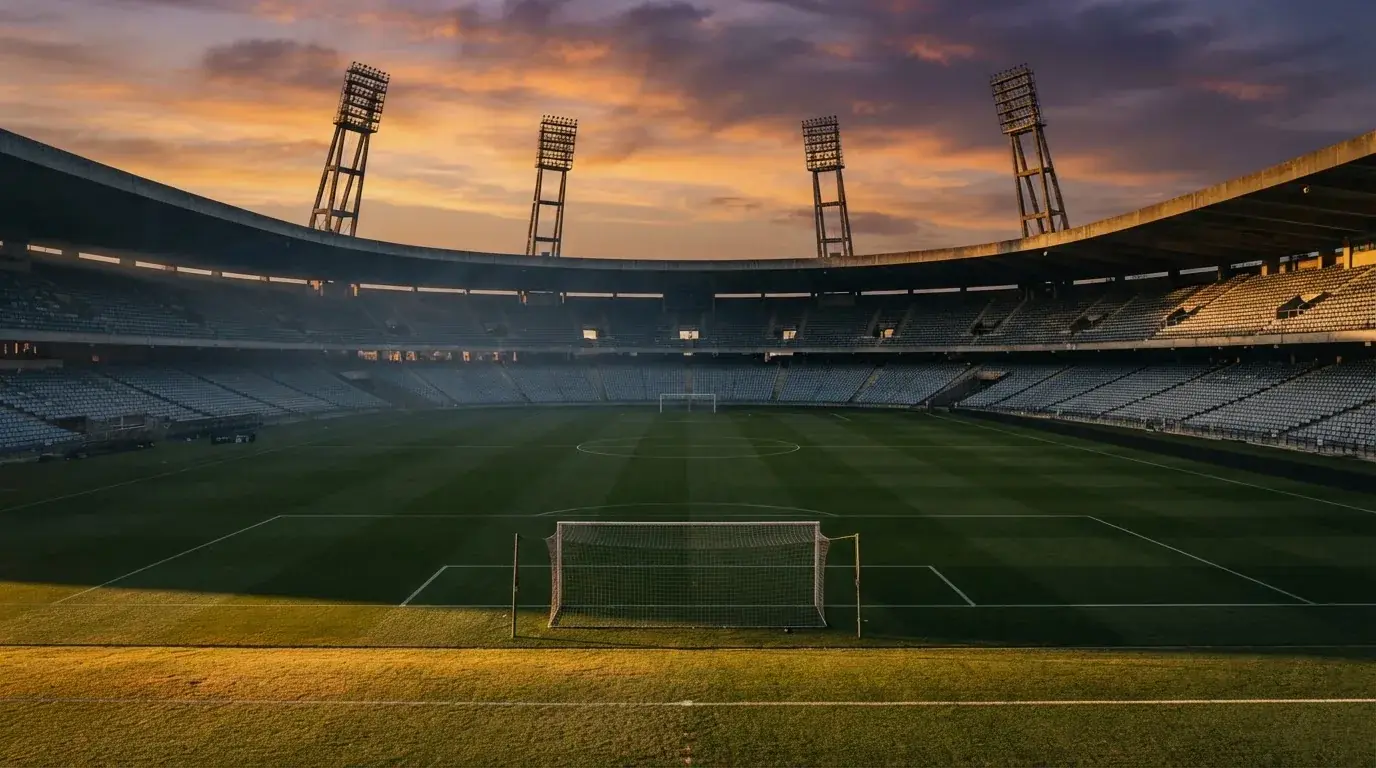 Un estadio de fútbol vacío con torres de iluminación al atardecer